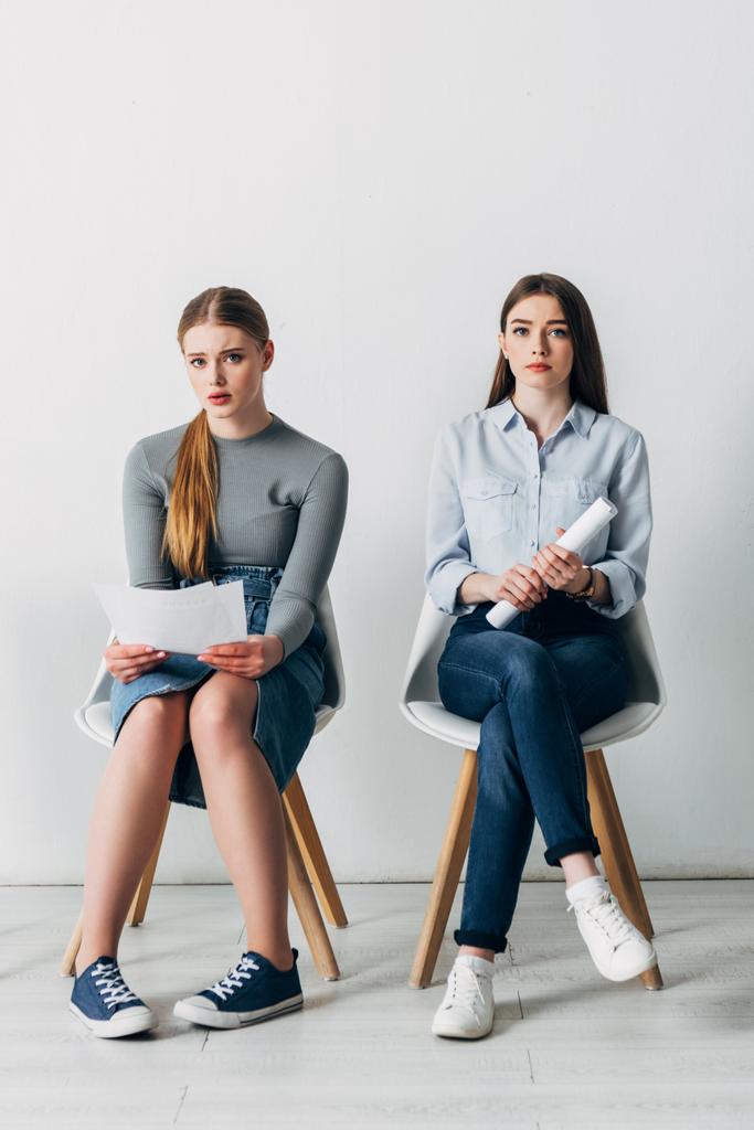 Attractive employees with resume looking at camera on chairs in office  - Photo, Image