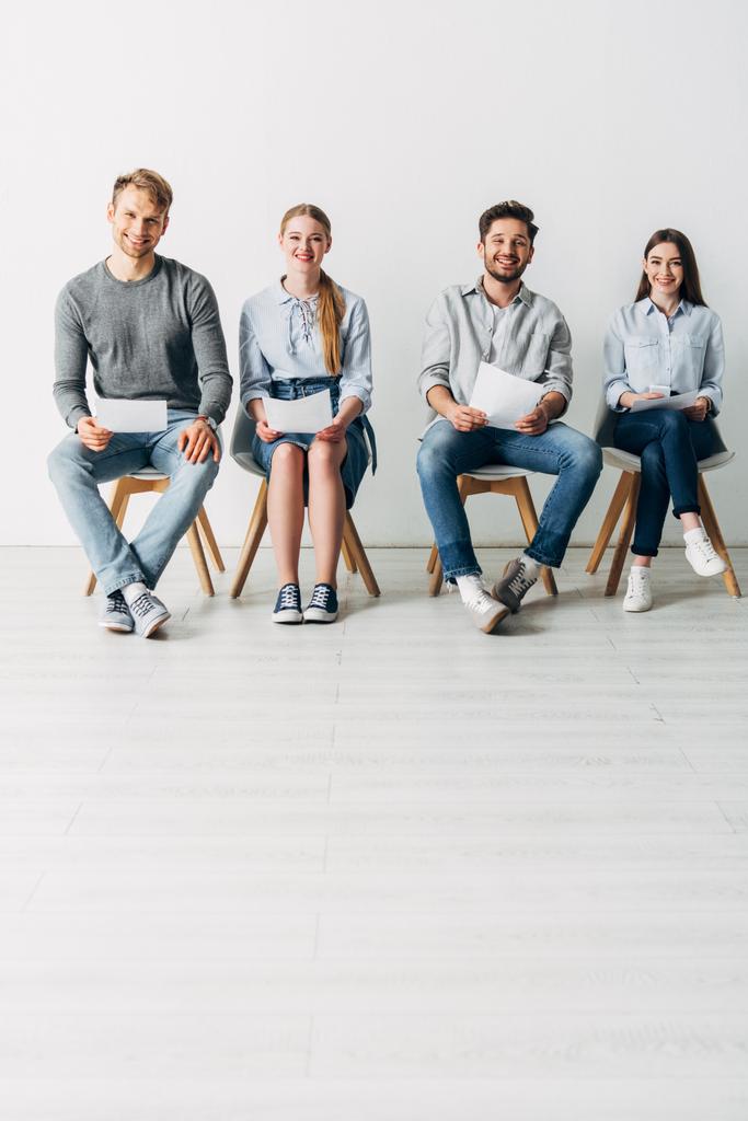 Gruppe junger Mitarbeiter mit Lebenslauf lächelt in Kamera im Büro  - Foto, Bild