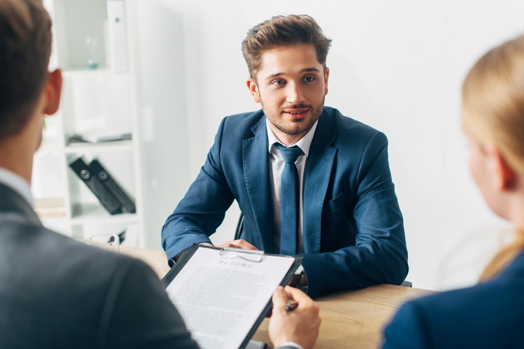 Enfoque selectivo del empleado guapo mirando al reclutador durante la entrevista de trabajo
 - Foto, imagen