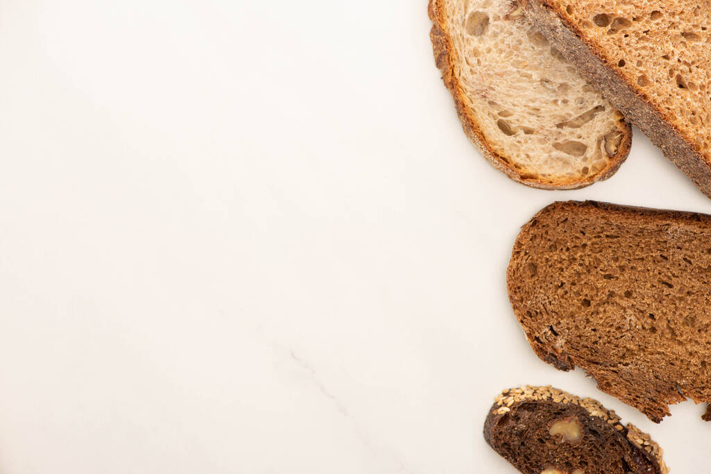 felső nézet friss teljes kiőrlésű kenyérszeletek fehér alapon - Fotó, kép