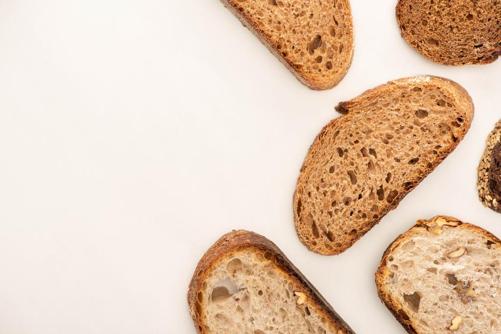 vista dall'alto di gustose fette di pane integrale su sfondo bianco con spazio copia
 - Foto, immagini