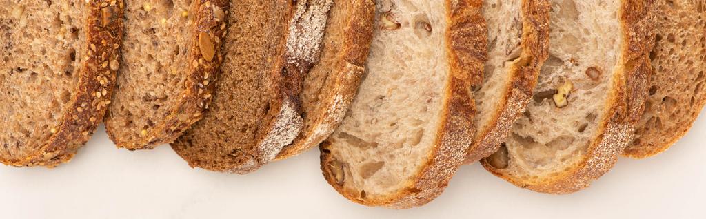 вид сверху на свежий цельнозерновой хлеб ломтики на белом фоне, панорамный снимок
 - Фото, изображение