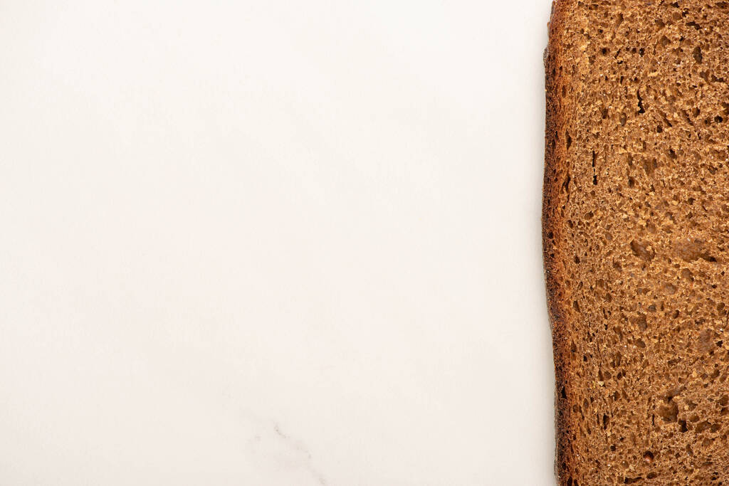 bovenaanzicht van vers bruin brood plak op witte achtergrond met kopieerruimte - Foto, afbeelding