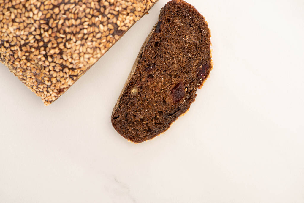 felső nézet friss barna kenyér szelet és kenyér fehér háttér - Fotó, kép