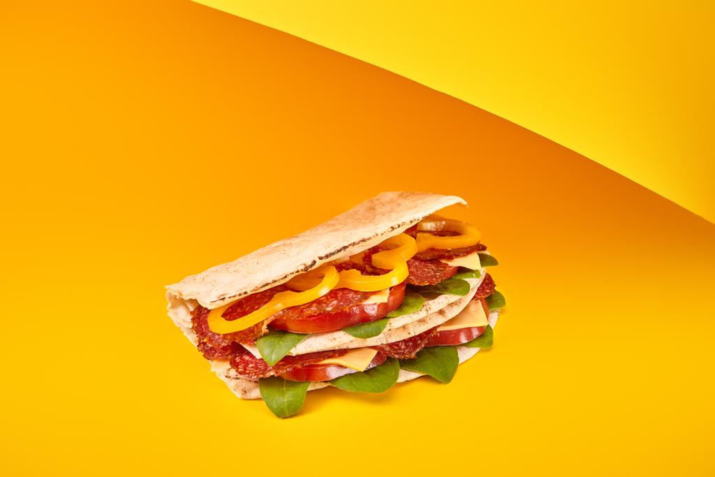 Sarı arka planda salamlı, pijamalı, sebzeli ve peynirli taze sandviç. - Fotoğraf, Görsel