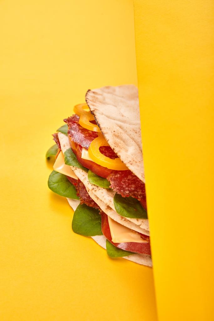 φρέσκο σάντουιτς με σαλάμι, πίτα, λαχανικά και τυρί σε κίτρινο φόντο - Φωτογραφία, εικόνα