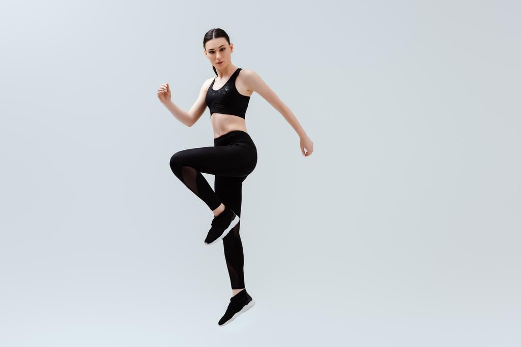 mulher esportiva em sportswear preto pulando isolado no branco
  - Foto, Imagem