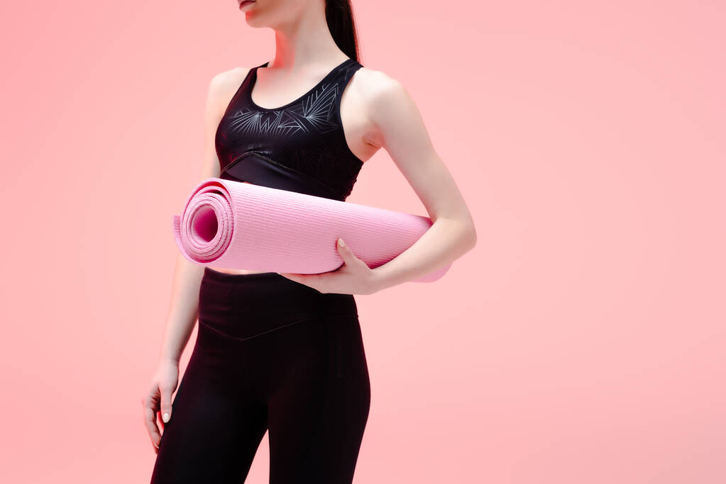 recortado vista de deportivo chica celebración de fitness mat aislado en rosa
  - Foto, imagen