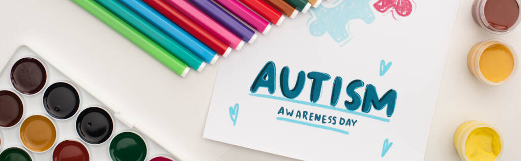 panoramic shot of card with Autism Awareness Day lettering and painting of puzzle on white with markers and paints - Photo, Image