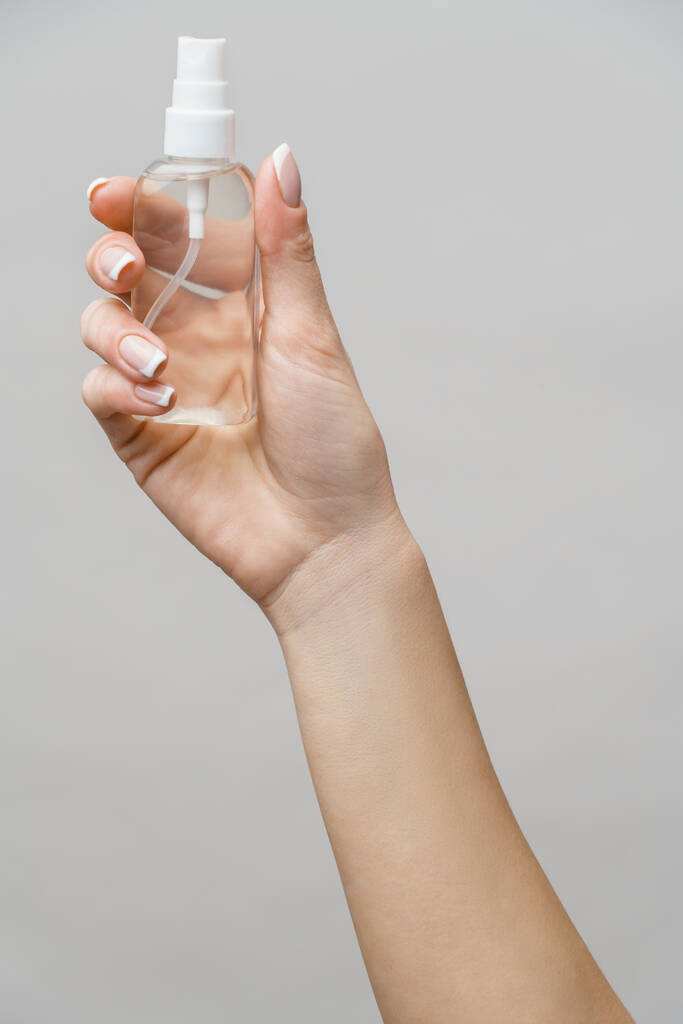 Vrouwelijke handen met behulp van handreiniger spray dispenser over lichtgrijze achtergrond - Foto, afbeelding