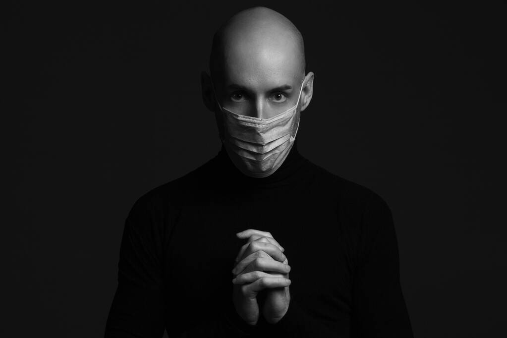 Coronavirus, Bio Protection Concept. Detailní portrét pohledného plešatého muže v lékařské masce, černém roláku a modlící se. Rozumím, vesmíre. Studio shot - Fotografie, Obrázek