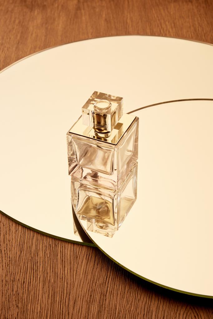 Skleněná láhev parfému na kulatém béžovém zrcadlovém povrchu - Fotografie, Obrázek