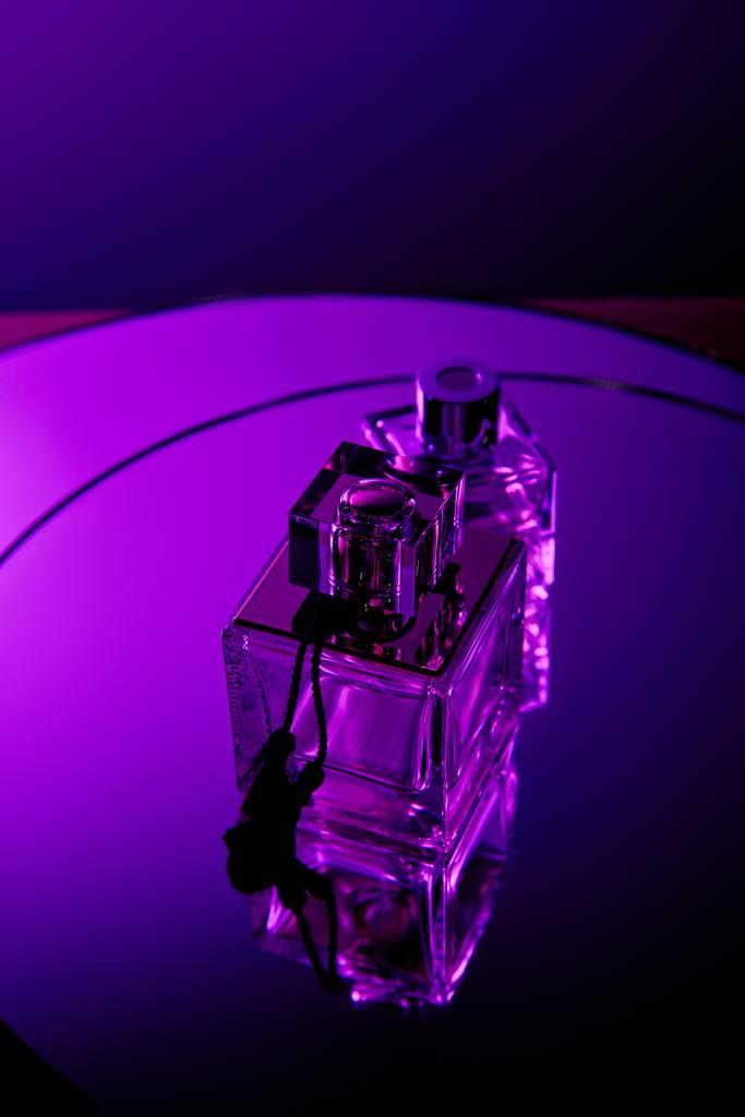 Vista superior de frascos de perfume na superfície escura do espelho violeta redondo
 - Foto, Imagem