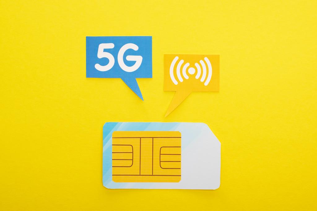 πάνω όψη της κάρτας sim και φυσαλίδες ομιλίας με γράμματα 5g σε κίτρινο φόντο - Φωτογραφία, εικόνα