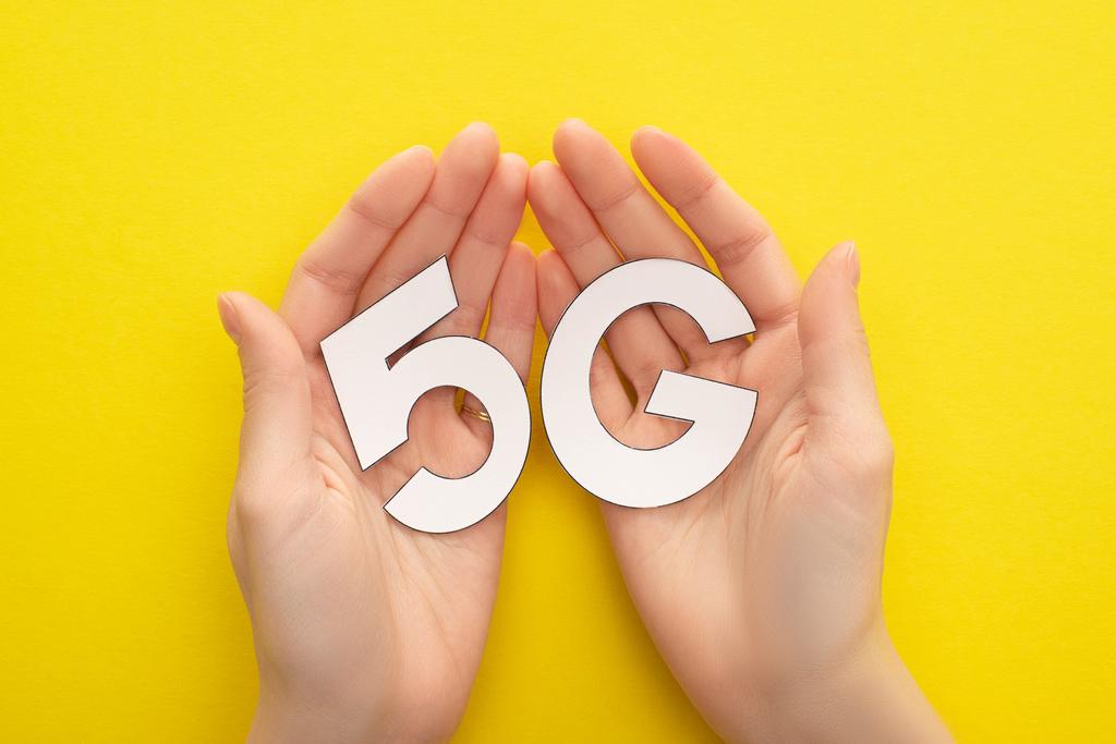 cropped view of woman holding white 5g lettering on yellow background - Photo, Image