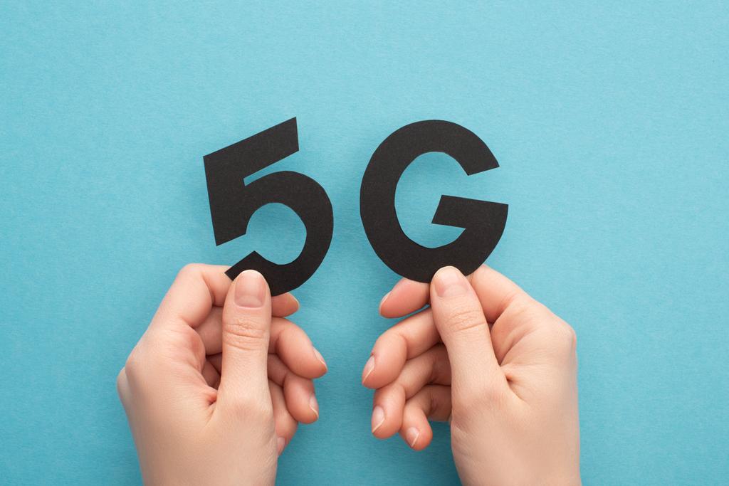 cropped view of woman holding black 5g lettering on blue background - Photo, Image