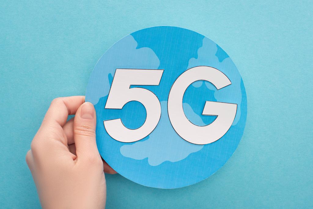 cropped view of woman holding white 5g lettering on globe on blue background - Photo, Image