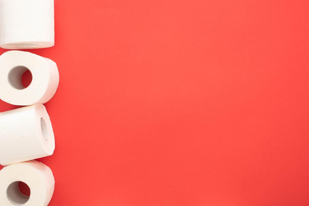 Κάτοψη του λευκού χαρτιού υγείας ρολά σε κόκκινο φόντο με χώρο αντίγραφο - Φωτογραφία, εικόνα