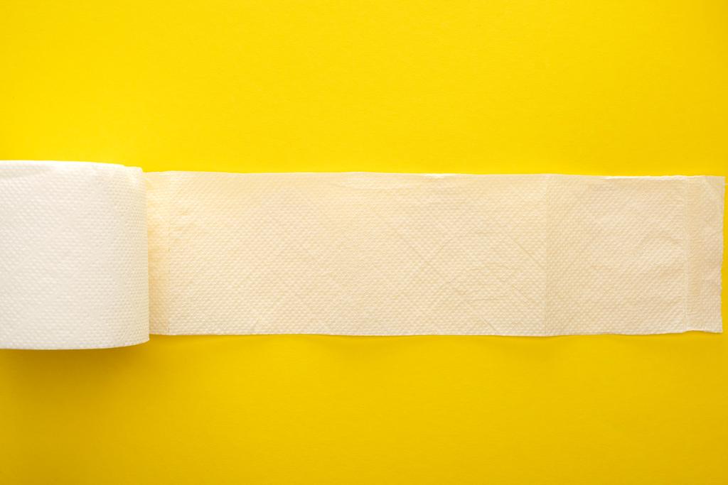 vista superior de papel higiênico branco desenrolado no fundo amarelo
 - Foto, Imagem