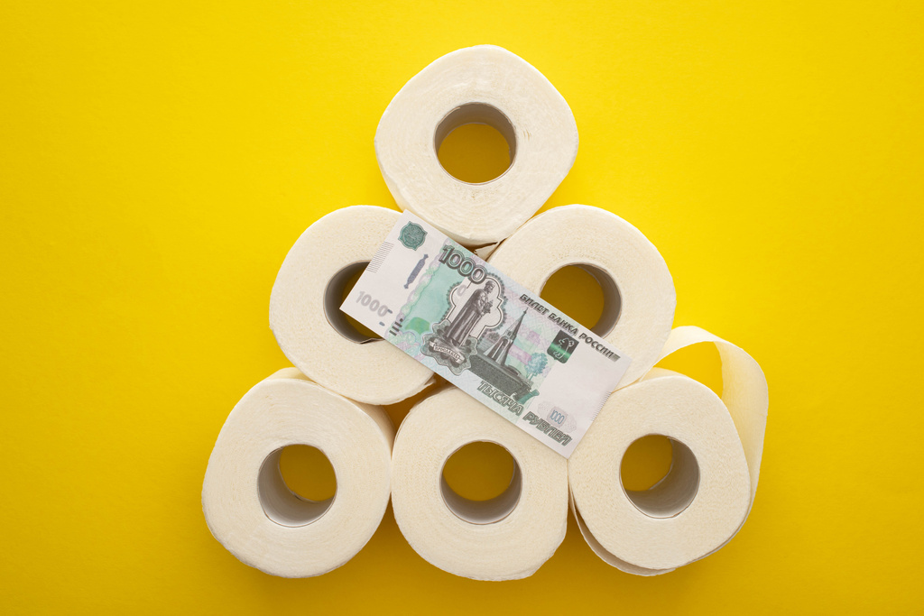 vista dall'alto di rotoli di carta igienica bianca disposti in piramide con soldi russi su sfondo giallo
 - Foto, immagini