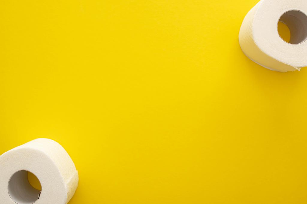 bovenaanzicht van schoon toiletpapier rollen op gele achtergrond met kopieerruimte - Foto, afbeelding
