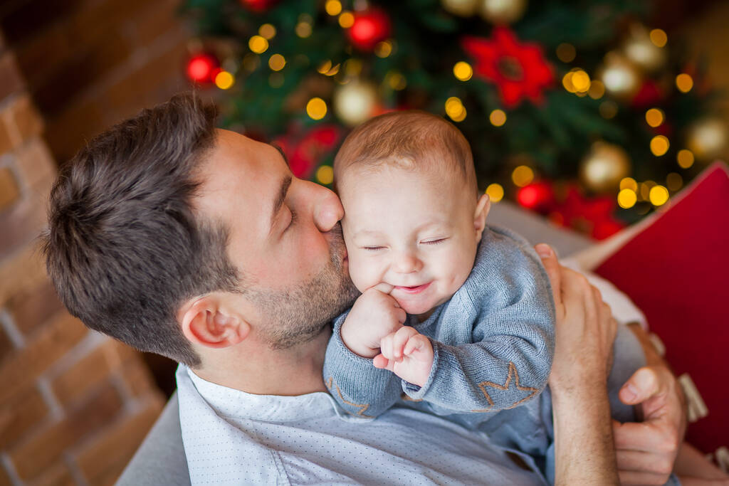 vader knuffels pasgeboren zoon kerst tijd - Foto, afbeelding