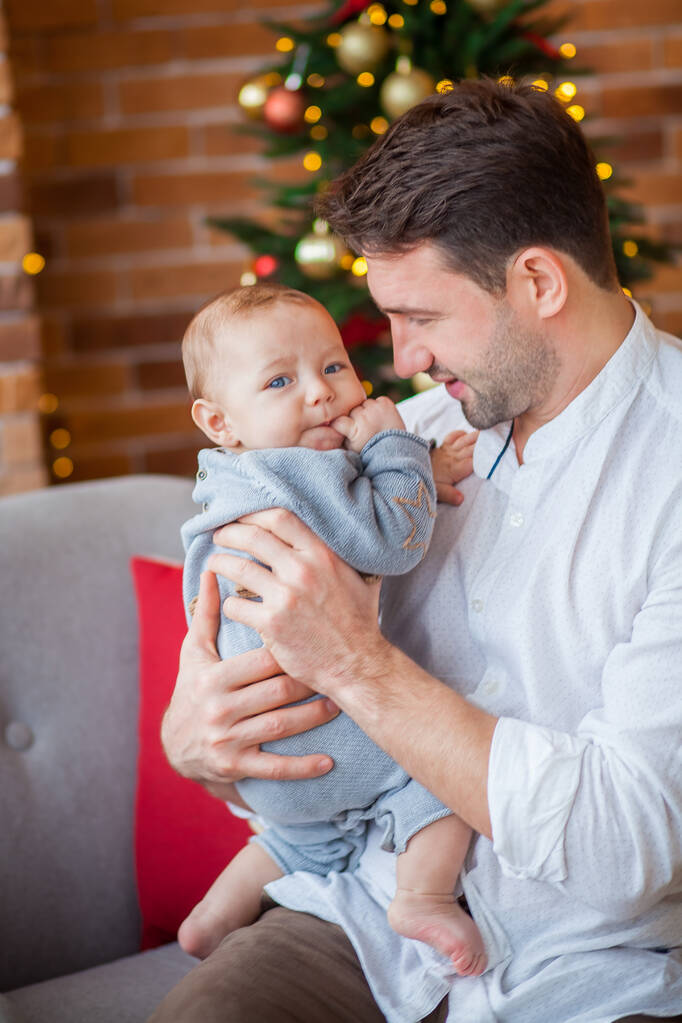 Papa umarmt neugeborenen Sohn Weihnachtsbeleuchtung - Foto, Bild