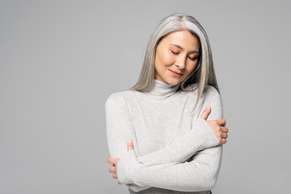 dreamy asian woman in turtleneck with grey hair and closed eyes isolated on grey - Photo, Image