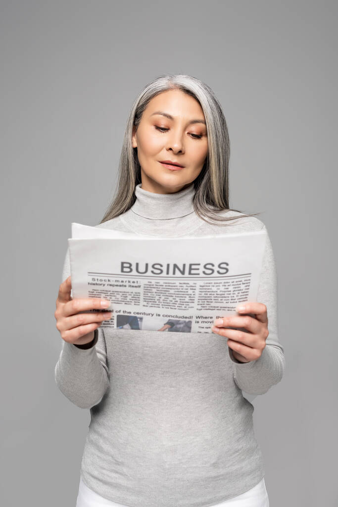 magabiztos ázsiai nő szürke hajjal olvasás üzleti újság elszigetelt szürke - Fotó, kép