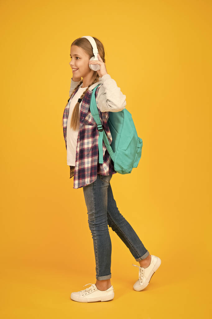 Készen állok. hipszter lány gondoskodó hátizsák. iskoláslány alkalmi stílus tartsa iskolai táska. Őszi gyerek divat. gyermek zenét hallgatni headset. gyermekkori oktatás és fejlesztés. Boldog gyermeknapot! hangoskönyv - Fotó, kép