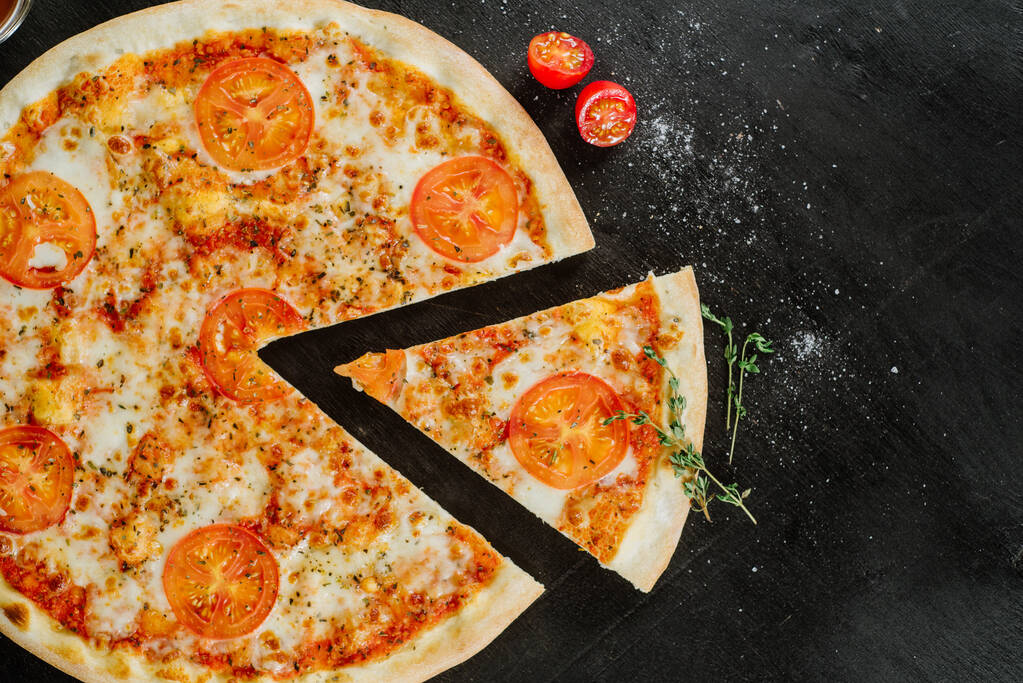 Sabrosa pizza con queso doble y tomates sobre fondo negro
 - Foto, Imagen