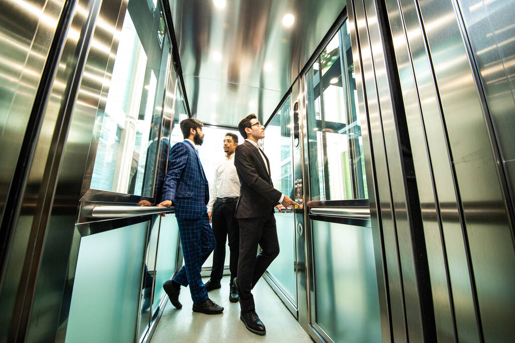 Groupe d'affaires en ascenseur. Les gens d'affaires dans un grand ascenseur en verre dans un bureau moderne. Entreprises d'entreprisevapeur et directeur dans une réunion. - Photo, image