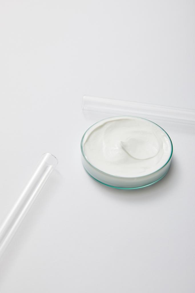 Vetreria da laboratorio con crema cosmetica bianca e provette su fondo grigio
 - Foto, immagini