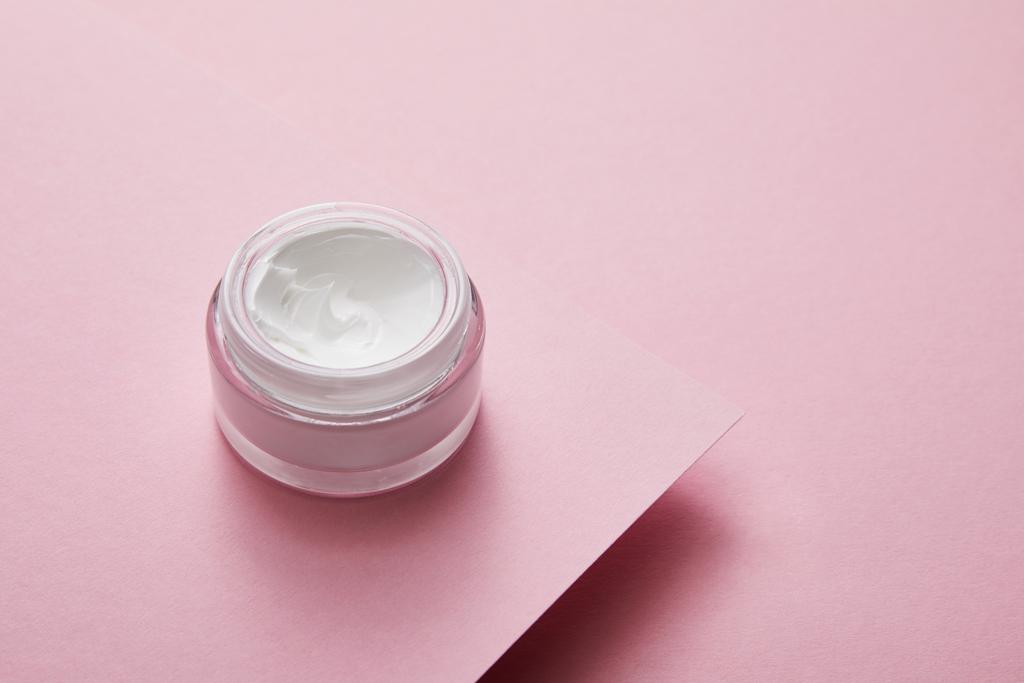Vue grand angle de la crème cosmétique en pot de verre sur fond de papier rose
  - Photo, image