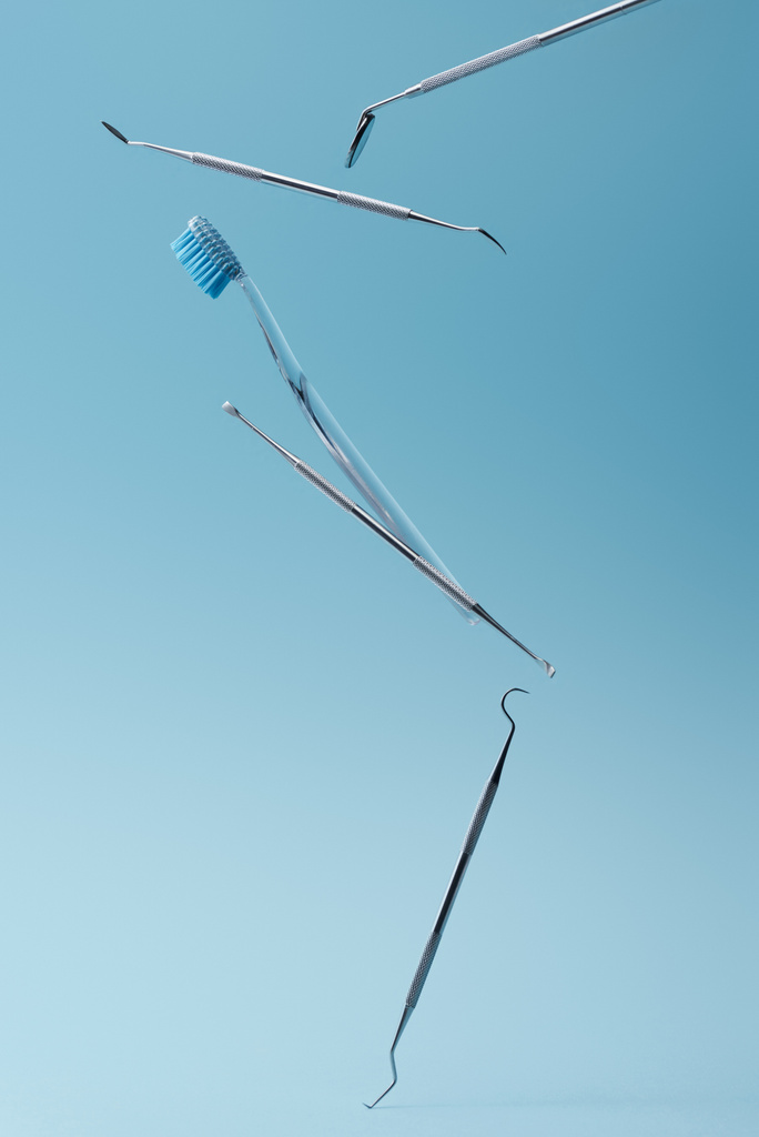 Zahnarztinstrumente und Zahnbürste schweben auf blauem Hintergrund - Foto, Bild