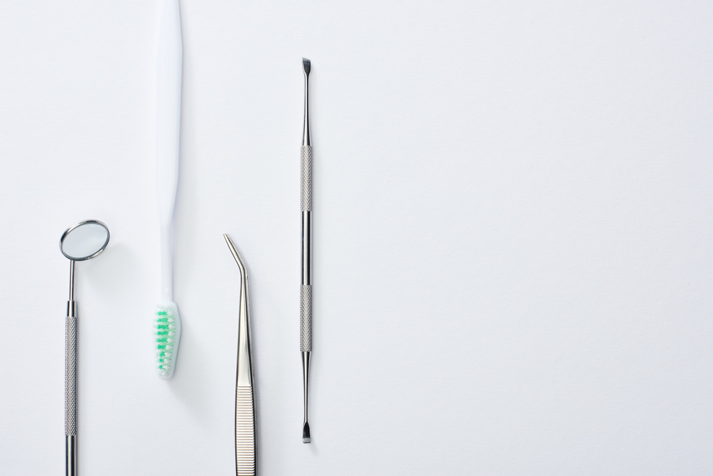 Bovenaanzicht van tandheelkundige instrumenten en tandenborstel op grijze achtergrond - Foto, afbeelding
