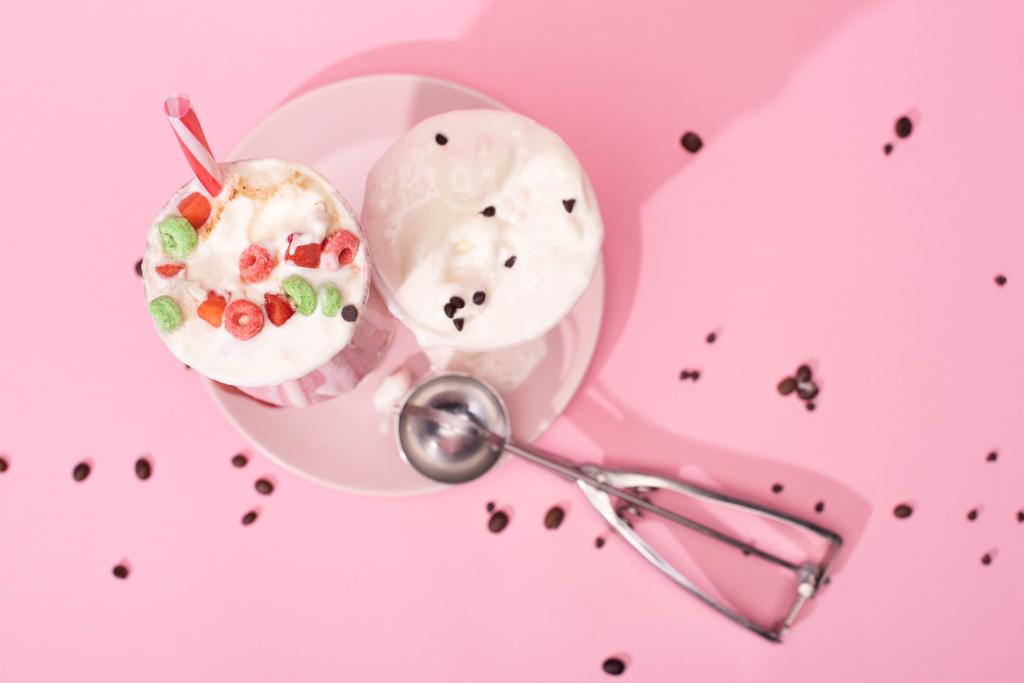 Vue du dessus de milkshakes fraise et scoop sur plaque avec grains de café sur rose
  - Photo, image