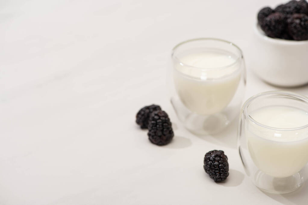 Wysoki kąt widzenia szklanek jogurtu domowej roboty i jeżyn na białym tle - Zdjęcie, obraz