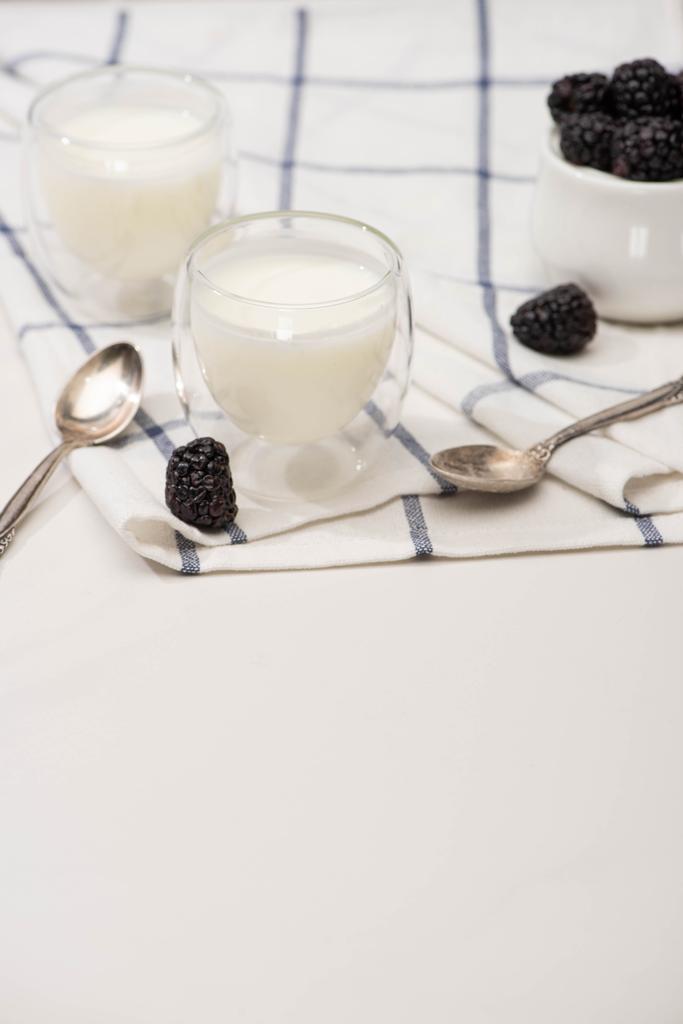 Concentration sélective de verres de yaourt maison, cuillères à café et bol à sucre avec mûres sur tissu sur blanc
  - Photo, image
