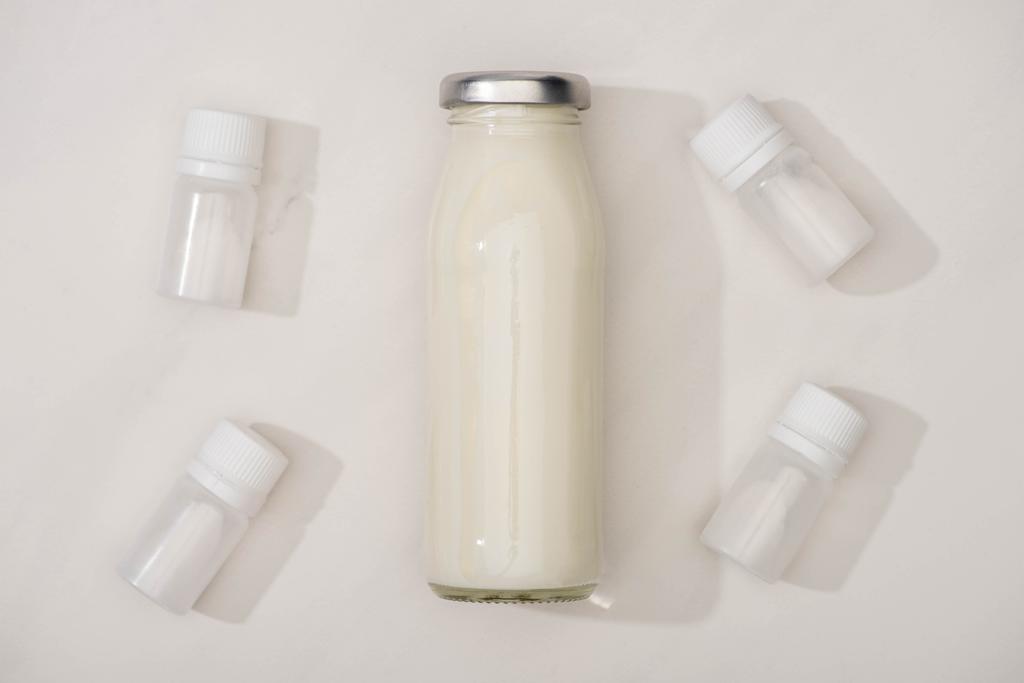 Horní pohled na láhev domácího jogurtu a nádoby se startérem kultur na bílém pozadí - Fotografie, Obrázek