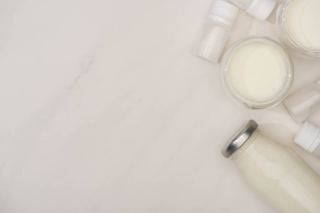 Vista dall'alto di bottiglia e bicchieri di yogurt e contenitori fatti in casa con colture di antipasto su sfondo bianco
 - Foto, immagini