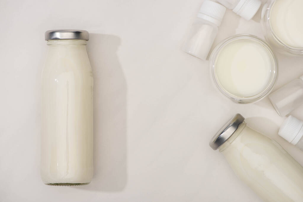 Вид сверху бутылок и стаканов домашнего йогурта и контейнеров со стартерными культурами на белом фоне
 - Фото, изображение