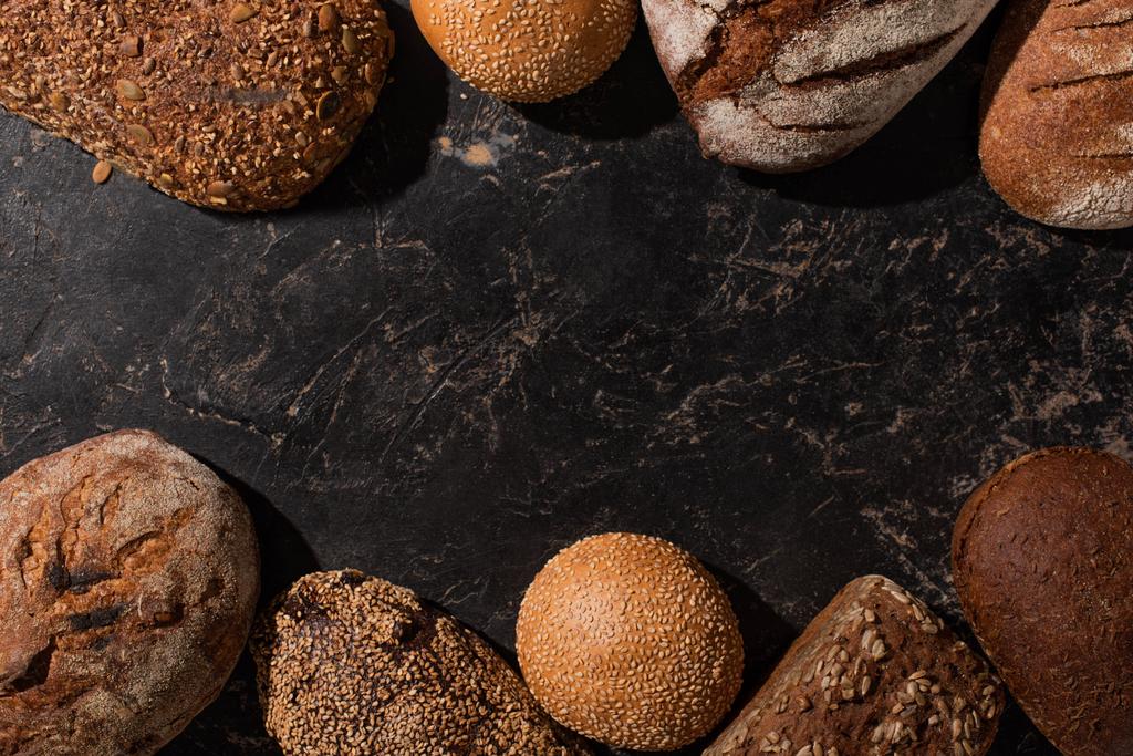 top view of fresh baked bread and buns on stone black surface - Photo, Image