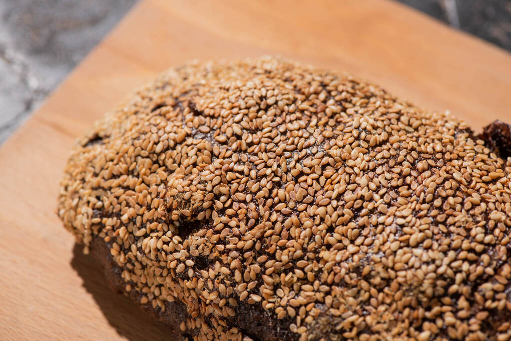 свежий выпеченный черный хлеб с кунжутом на доске
 - Фото, изображение