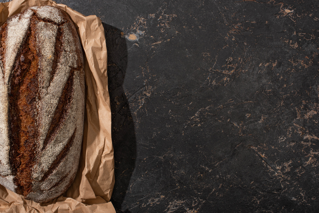 ylhäältä näkymä orgaaninen ruskea leipä leipä paperilla kiven musta pinta
 - Valokuva, kuva