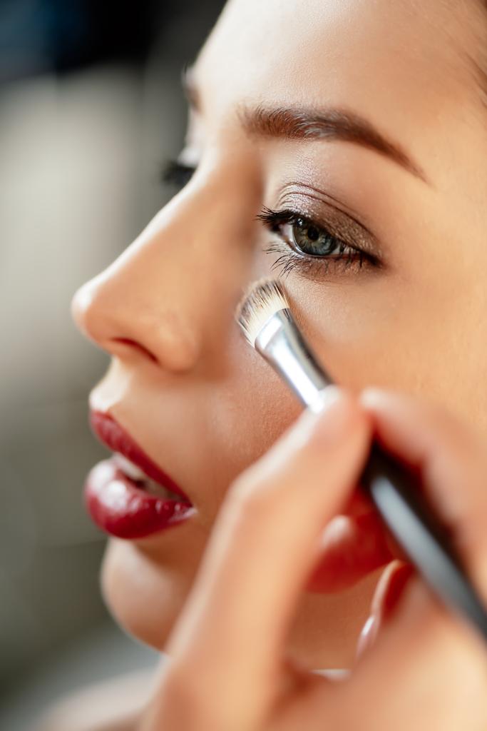 selective focus of makeup artist applying concealer on model  - Photo, Image