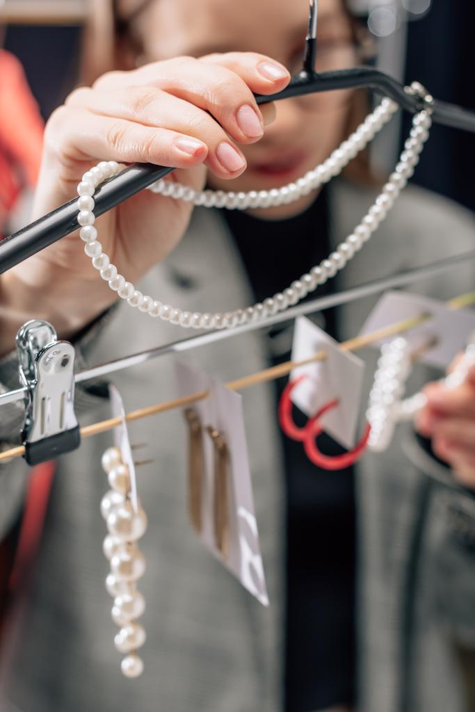 selektivní zaměření stylistky dotýkající se perlového náhrdelníku v blízkosti náušnic  - Fotografie, Obrázek