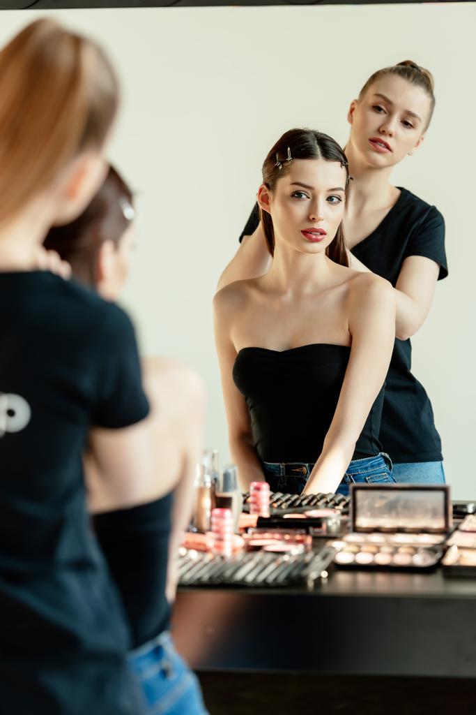 selective focus of make up artist near model and decorative cosmetics  - Photo, Image