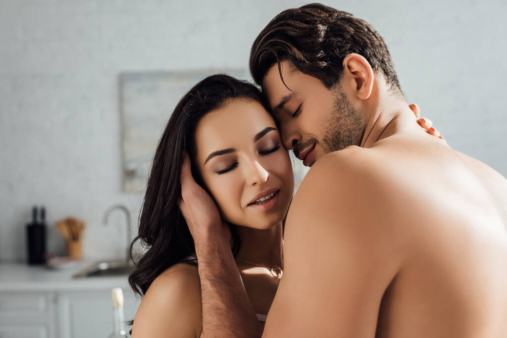 Casal apaixonado com olhos fechados abraçando na cozinha
 - Foto, Imagem
