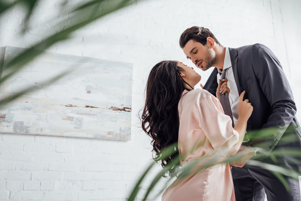 Szelektív fókusz üzletember és barátnő húzza férfi nyakkendő a hálószobában - Fotó, kép